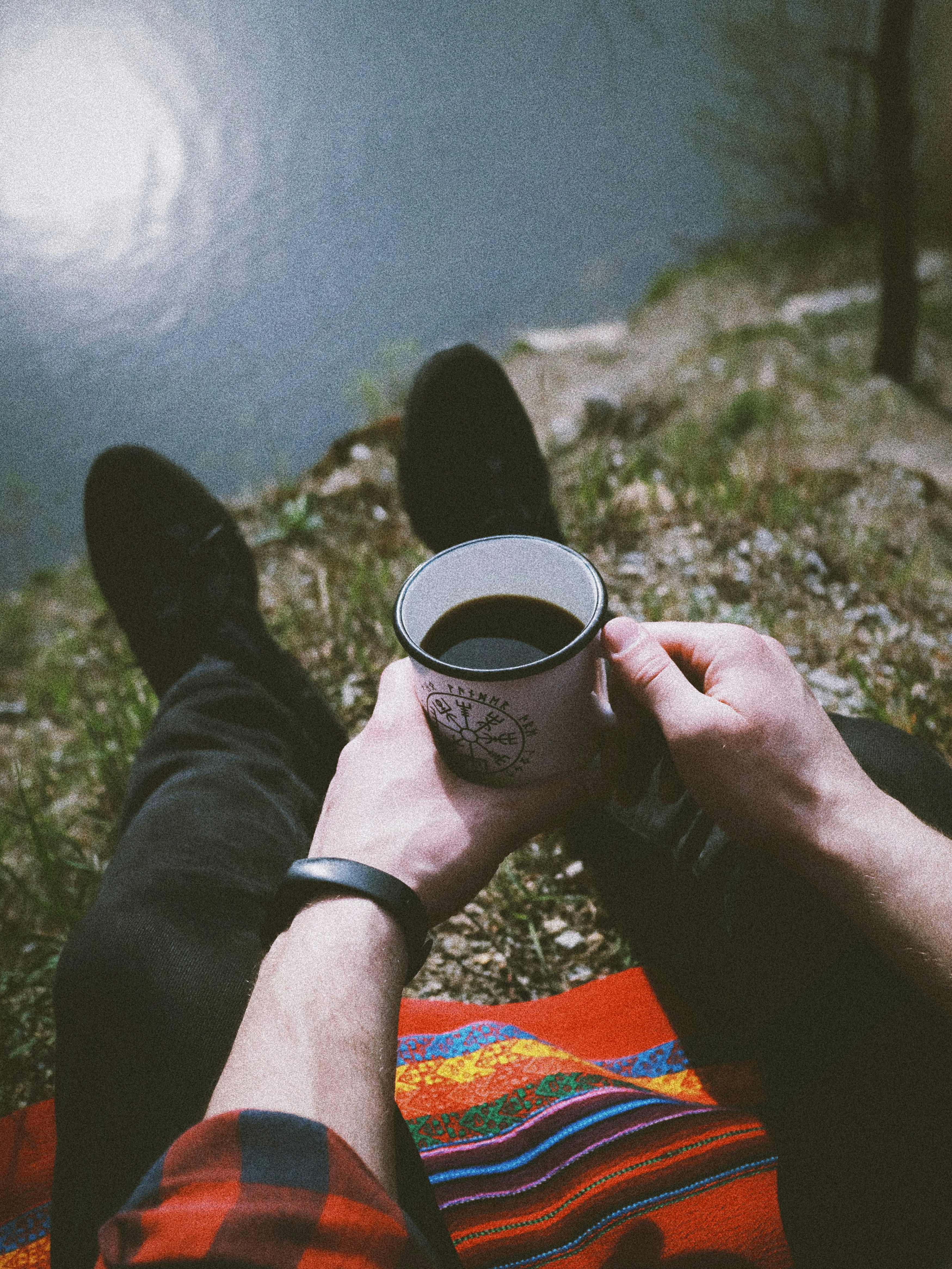 person holding black ceramic mug filled with black coffee